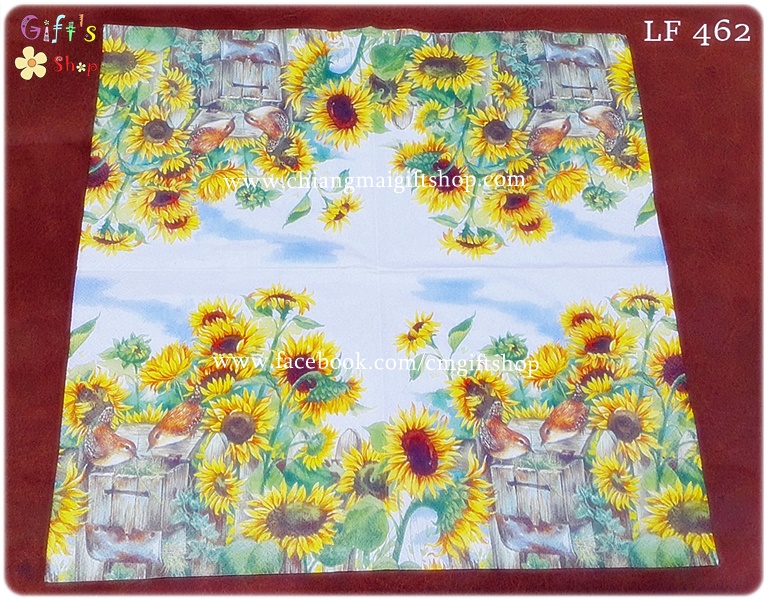 กระดาษแนปกิ้น ลายทุ่งดอกทานตะวันสีเหลืองสดใสใบสีเขียว มีนกสีส้มน้ำตาลกินอาหารนกบนลังไม้ที่ให้อาหารนก พื้นหลังท้องฟ้าและเมฆสีขาว
